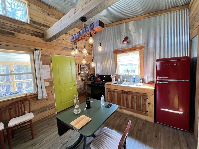 kitchen with black gas range oven, decorative light fixtures, wooden walls, and refrigerator