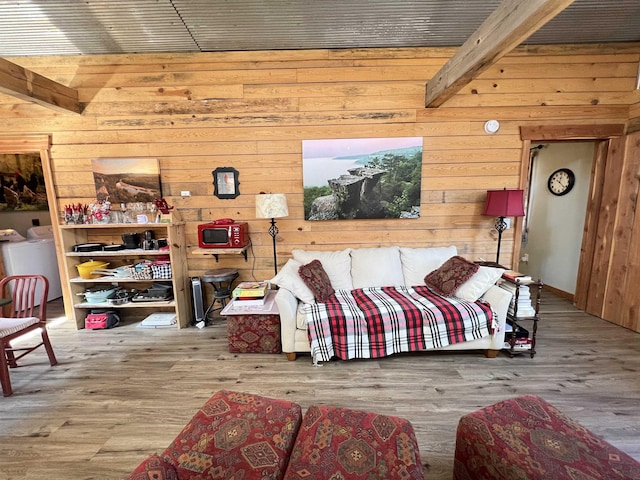 bedroom featuring hardwood / wood-style flooring, wood walls, washer / clothes dryer, and beamed ceiling