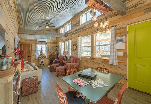 dining area with plenty of natural light, a wall mounted air conditioner, wooden walls, and light hardwood / wood-style floors