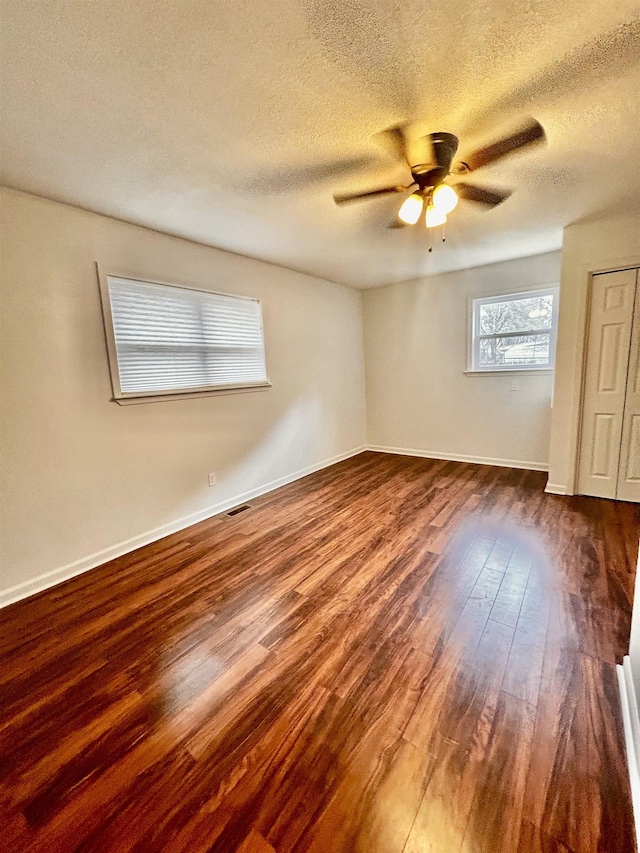 spare room with ceiling fan, dark hardwood / wood-style floors, and a textured ceiling