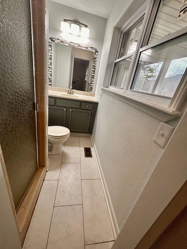 bathroom with walk in shower, vanity, and toilet