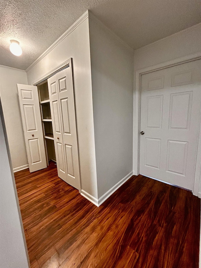 hall with ornamental molding, a textured ceiling, and dark hardwood / wood-style flooring