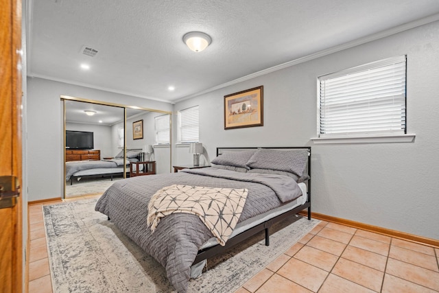 bedroom with crown molding, light tile patterned flooring, a textured ceiling, and a closet