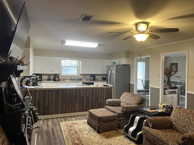 kitchen with white cabinets, stainless steel fridge, ceiling fan, kitchen peninsula, and light hardwood / wood-style flooring