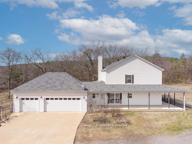 view of front of home featuring roof with shingles, a garage, driveway, and a chimney