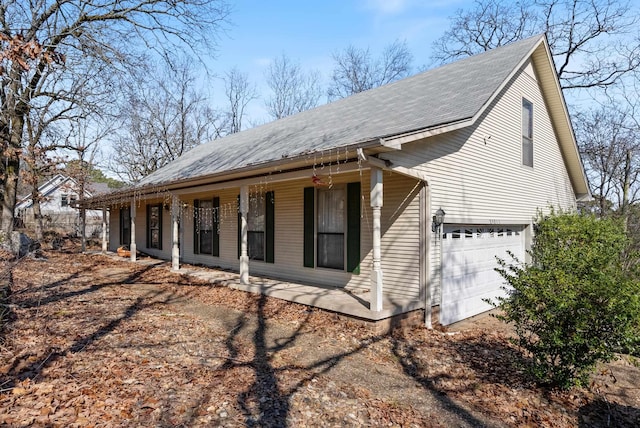 view of side of home featuring a garage and covered porch