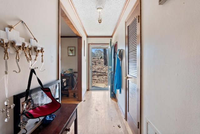 doorway with crown molding, wood-type flooring, and a textured ceiling