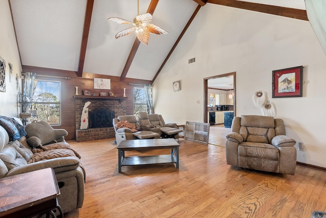 living room with high vaulted ceiling, beamed ceiling, ceiling fan, light hardwood / wood-style floors, and a brick fireplace