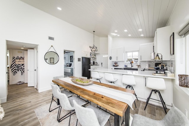 dining room featuring high vaulted ceiling, sink, wood ceiling, and light wood-type flooring