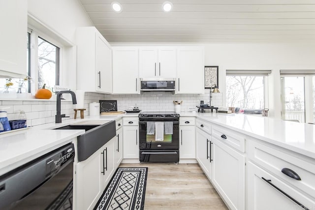 kitchen featuring light wood-type flooring, white cabinets, sink, and black appliances