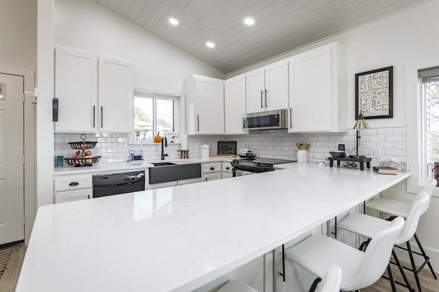 kitchen featuring white cabinetry, stainless steel appliances, a breakfast bar, and kitchen peninsula