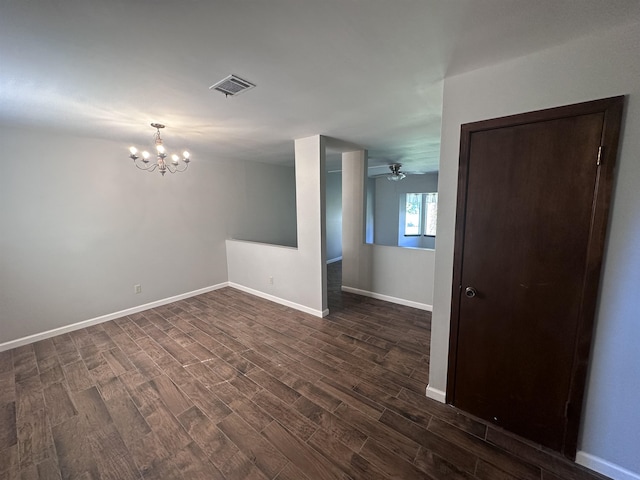 spare room with ceiling fan with notable chandelier and dark hardwood / wood-style flooring