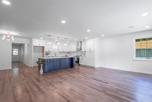 kitchen featuring decorative light fixtures, a center island, electric range, white cabinets, and wall chimney range hood