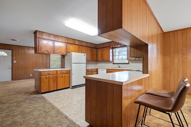 kitchen with white appliances, wooden walls, kitchen peninsula, and a breakfast bar