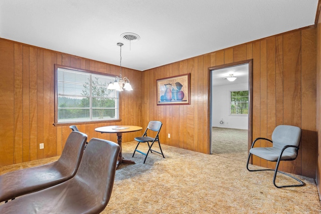 dining area with carpet flooring, an inviting chandelier, and wood walls