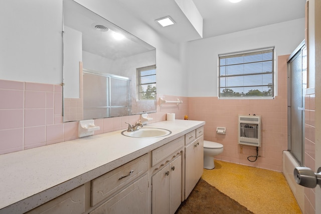 full bathroom with enclosed tub / shower combo, tile walls, heating unit, vanity, and toilet