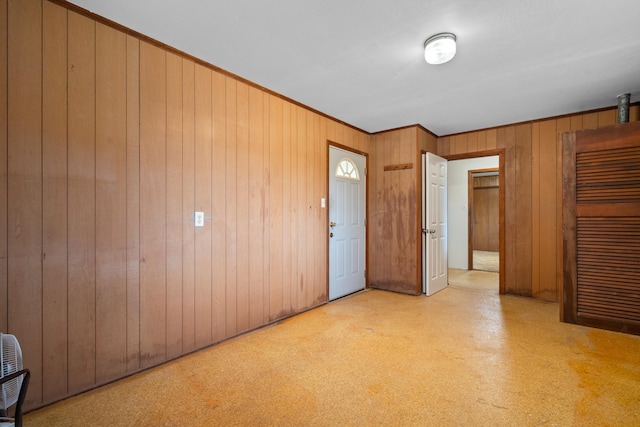unfurnished room featuring crown molding and wooden walls