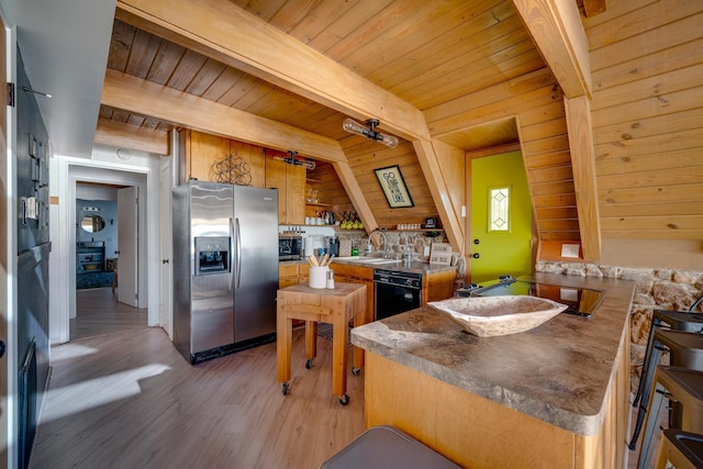 kitchen with stainless steel fridge, black dishwasher, kitchen peninsula, beam ceiling, and hardwood / wood-style floors