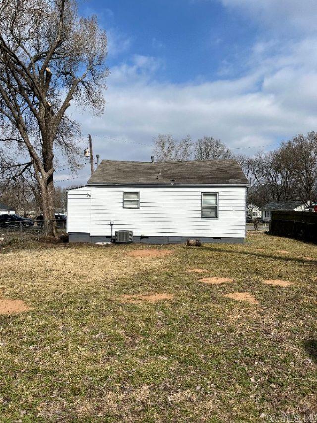 back of house with central AC unit and a lawn