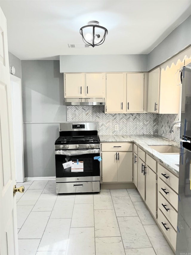 kitchen featuring stainless steel appliances, sink, cream cabinets, and backsplash