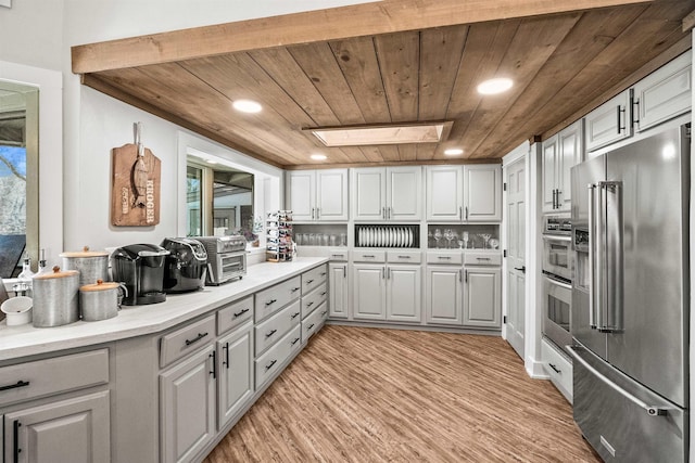 kitchen featuring gray cabinetry, wood ceiling, high end refrigerator, a skylight, and light hardwood / wood-style flooring