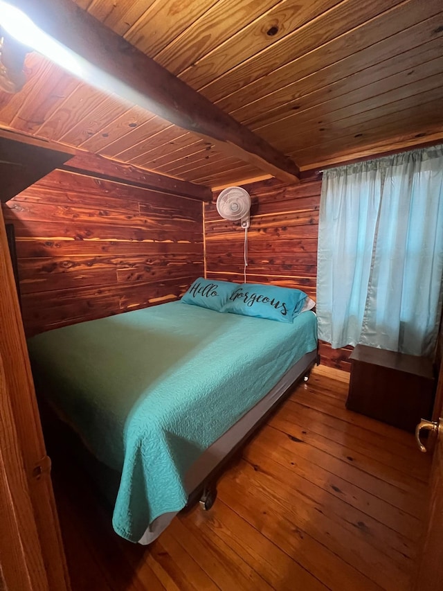 bedroom with wood ceiling, beam ceiling, wooden walls, and wood finished floors