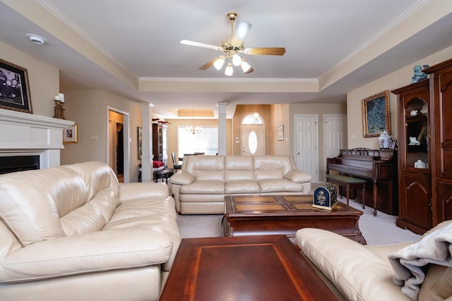 carpeted living room with decorative columns, ornamental molding, and ceiling fan with notable chandelier