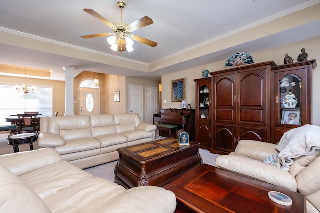 living room featuring decorative columns, ornamental molding, and ceiling fan with notable chandelier