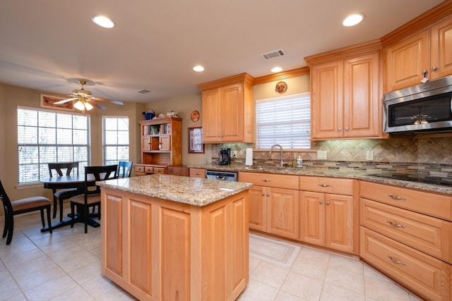 kitchen featuring appliances with stainless steel finishes, sink, a center island, light stone countertops, and light brown cabinets