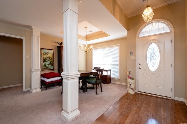 entrance foyer featuring ornamental molding, light hardwood / wood-style floors, a chandelier, and ornate columns