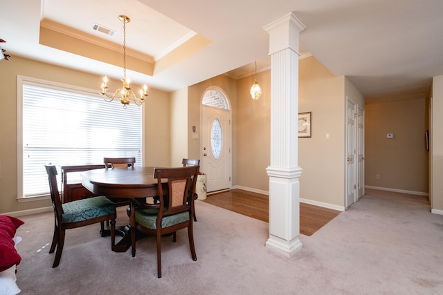 dining area featuring carpet, a tray ceiling, ornamental molding, and ornate columns