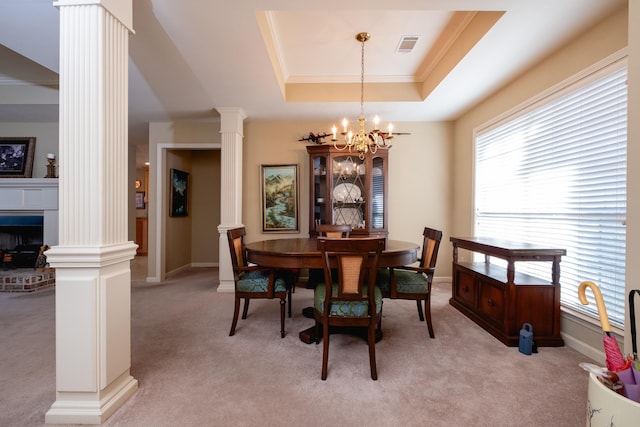 dining room featuring light carpet, a tray ceiling, crown molding, and ornate columns