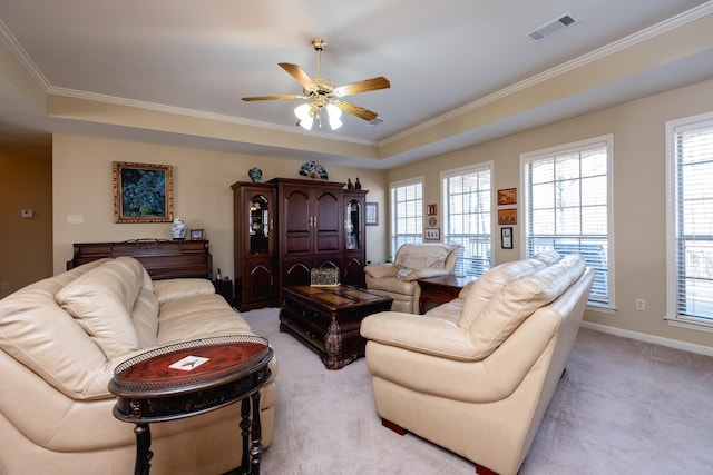 carpeted living room featuring a raised ceiling, ornamental molding, a wealth of natural light, and ceiling fan