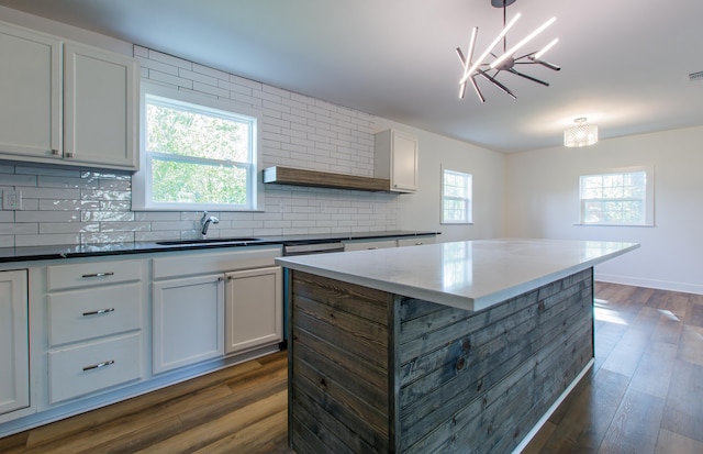 kitchen with white cabinetry, a kitchen island, sink, and hanging light fixtures