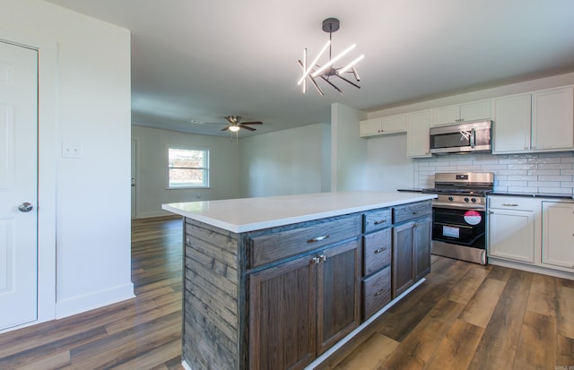 kitchen featuring decorative light fixtures, stainless steel appliances, dark hardwood / wood-style floors, and white cabinets