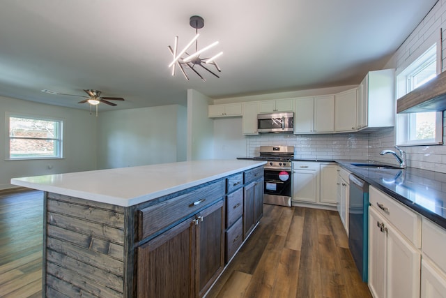 kitchen featuring pendant lighting, sink, stainless steel appliances, white cabinets, and dark hardwood / wood-style flooring