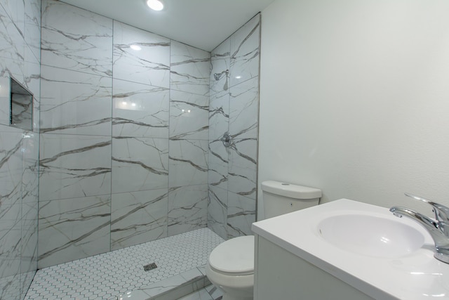 bathroom with vanity, toilet, and tiled shower