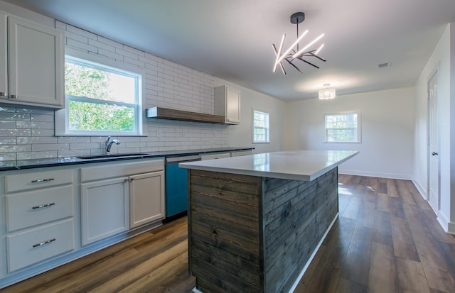 kitchen with sink, dark hardwood / wood-style floors, a center island, decorative light fixtures, and stainless steel dishwasher