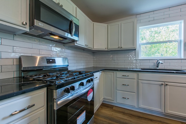 kitchen with dark wood-type flooring, sink, appliances with stainless steel finishes, decorative backsplash, and white cabinets