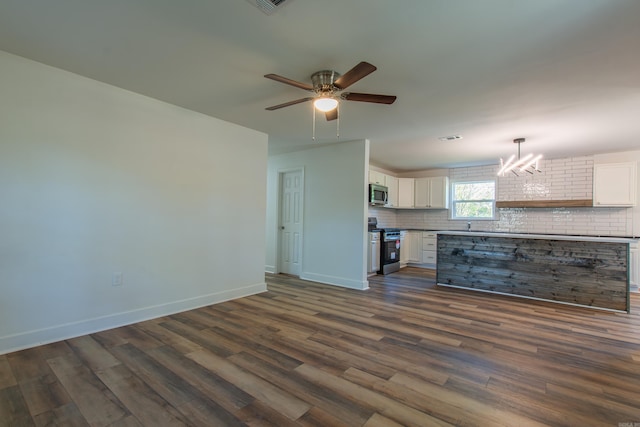 unfurnished living room featuring dark hardwood / wood-style floors and ceiling fan with notable chandelier