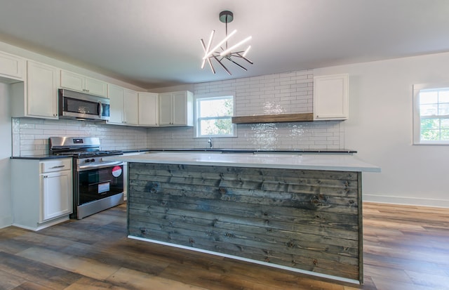 kitchen with white cabinetry, stainless steel appliances, decorative light fixtures, and sink