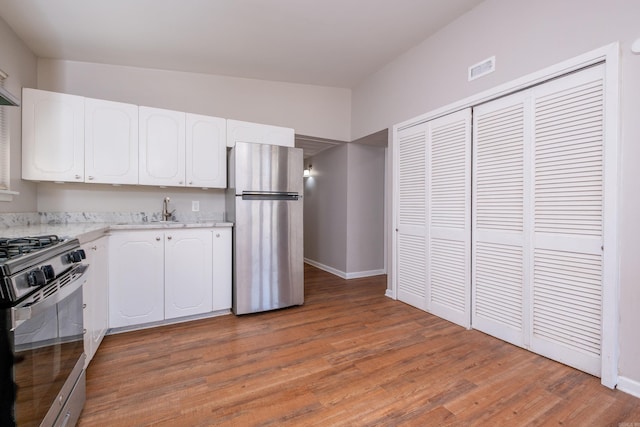 kitchen featuring sink, wood-type flooring, stainless steel appliances, and white cabinets