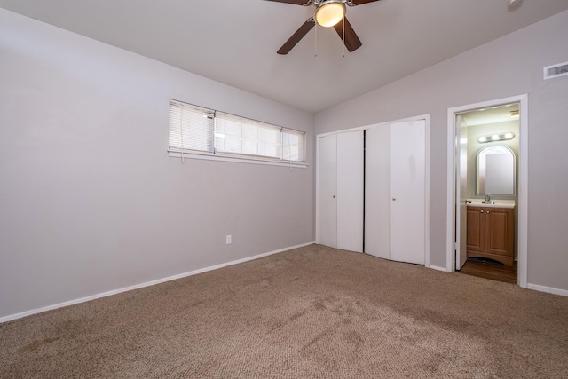 unfurnished bedroom with vaulted ceiling, ensuite bathroom, carpet floors, ceiling fan, and a closet