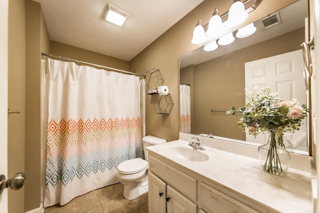 bathroom with tile patterned floors, toilet, vanity, and a textured ceiling