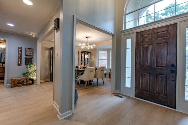 entrance foyer featuring a notable chandelier, ornamental molding, and light wood-type flooring