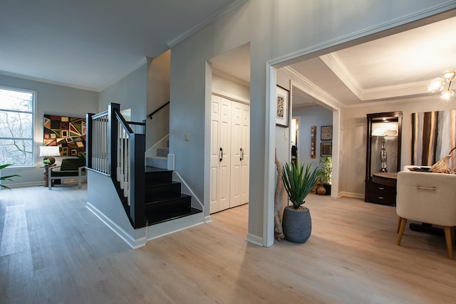 foyer entrance with an inviting chandelier, ornamental molding, and light hardwood / wood-style floors