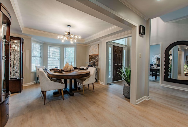 dining area featuring a raised ceiling, ornamental molding, an inviting chandelier, and light hardwood / wood-style floors