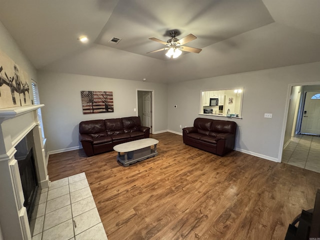 living room featuring lofted ceiling, a fireplace, wood-type flooring, and ceiling fan