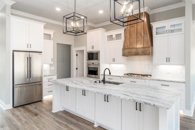 kitchen with stainless steel appliances, sink, white cabinets, and a large island with sink