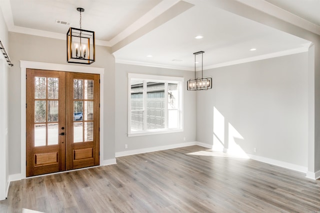 foyer featuring a notable chandelier, hardwood / wood-style flooring, and ornamental molding